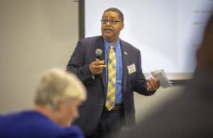 Engaged male speaker presenting at a conference on education and community development.