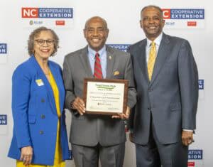 Three individuals pose with a certificate of appreciation at an event for Small Farms Week.