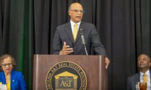 A man speaking at a podium during a formal event with the North Carolina Real Estate Foundation logo.