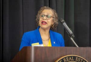 Elevated woman speaker at podium during conference or event.