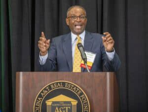 Affordable housing advocate speaking at a conference podium with North Carolina ACT logo.