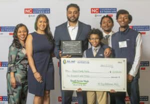 Four people gather, celebrating Brown Family Farms' Small Farms Week award and check for $2,000.