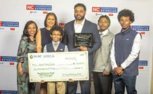 A family poses with a large check and award for "Small Farmer of the Year" during the NC Small Farms Week event.