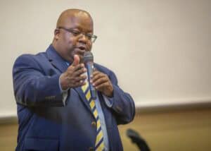 Professional man speaking at a conference or seminar in formal attire.