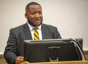 Professional man speaking at a conference or seminar in formal attire.