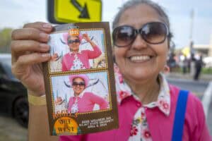 Woman holding a vintage-style photo booth strip at an outdoor event.