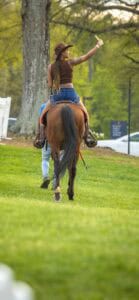 Rider on horseback taking a selfie in a park during daytime.