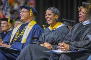 Graduation ceremony with diverse graduates in academic regalia celebrating achievement.