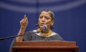Empowered woman speaking at a podium during a formal event or conference.