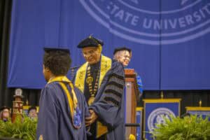 Graduation ceremony at a university with graduates in caps and gowns on stage.