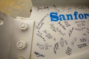 Signatures on a whiteboard with "Sanford" logo, representing community or team collaboration.