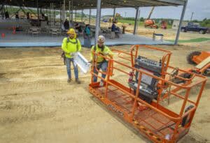 Excavation workers operating a boom lift at a construction site for CAES News.