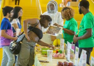 Fresh produce and healthy food options at a vibrant farmers market stall. Shoppers engage with vendo.