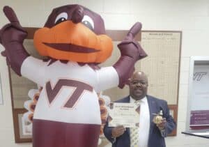 Virginia Tech mascot and alumnus celebrating graduation achievement indoors.
