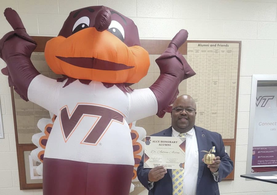 Virginia Tech mascot and alumnus celebrating graduation achievement indoors.