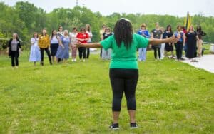 Empowering woman leading outdoor group activity with diverse participants on a sunny day.