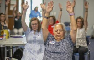 Elevated women participating in a workshop or seminar, raising hands in a gesture of engagement and.