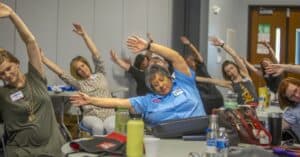 Stretching exercise session at CAES News workshop with diverse participants.