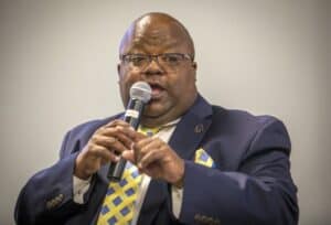 A man speaking into a microphone at a conference or event.