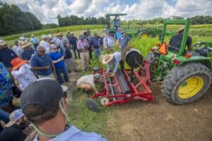 Agricultural training session with farmers and tractor demonstration in a lush green field.