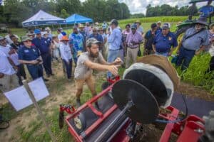 High-tech agricultural equipment demonstration at outdoor event with farmers and experts.