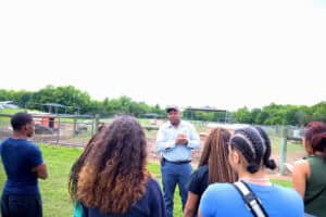Engaging outdoor educational session with diverse group of students and instructor at a farm or zoo.