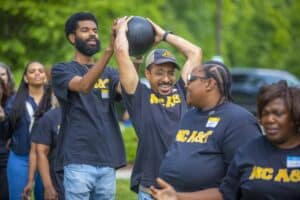 High school students participating in outdoor fitness activity with a medicine ball at CAES News eve.