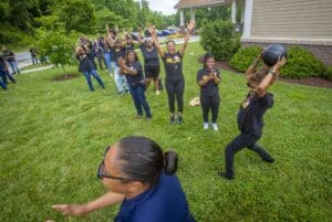 Outdoor team-building activity with children and adults playing with a medicine ball on a grassy law.