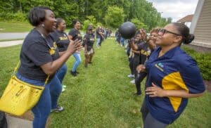 A group enjoys a fun outdoor game, smiling and tossing a ball between two lines of participants.