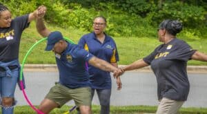 Happily interacting group of diverse people outdoors, engaging in team-building activity with a hula.