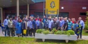 A large group of people poses together in front of a building marked "University Farm.