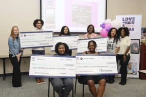 Empowerment award ceremony with diverse women holding large checks at CAES News event.