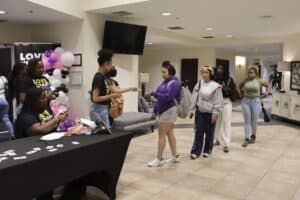 Group of young women registering at a community event desk in a modern indoor space.