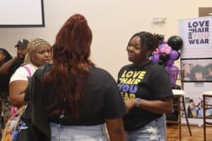 Empowered women engaging at CAES News event, promoting hair love and confidence in a community gathe.