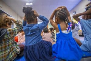 Children sitting on the floor during a classroom activity, engaging in learning and discussion.