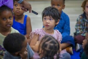 A young girl speaking to a group of children during an educational activity.