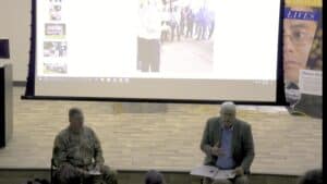 Business presentation with two speakers in front of a large screen at a conference.