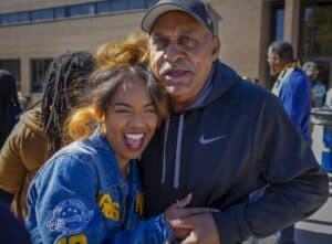 Happy young woman and older man smiling outdoors at a community event.