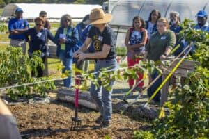 Planting demonstration with a group of people in a garden or farm setting.