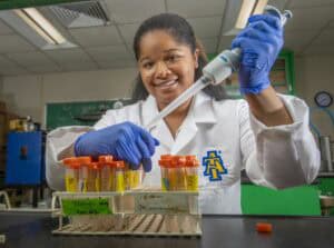 A woman scientist conducting laboratory research with test tubes and pipette in a science lab.