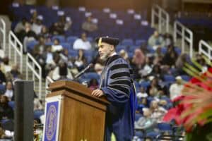 Graduation speaker delivering speech at university ceremony in academic regalia.
