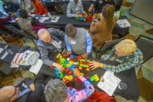 Builds and collaborates during a team activity with colorful blocks at a conference.