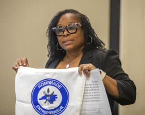 NC homemade entrepreneur logo on a bag held by a woman with glasses at a professional event.