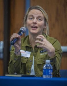 A woman identified as Mallory Choudoir, wearing an NC State Extension jacket, speaks into a microphone while seated at a table during a panel discussion.