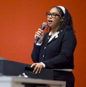 Empowered woman speaking into microphone at conference or event, delivering a speech.