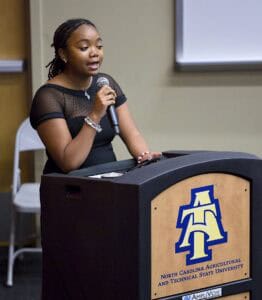 Empowered young woman speaking at podium during presentation or speech.