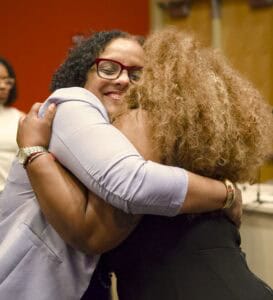 Empowering women in a warm hug at a community event for diversity and support.