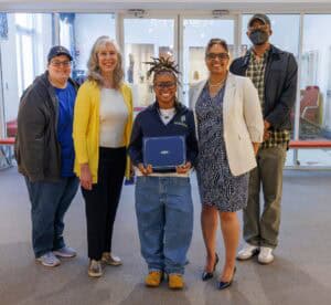 Empowered young woman receiving award from diverse group of professionals at CAES News event.