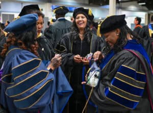 Graduates celebrating at a university commencement ceremony in academic regalia.