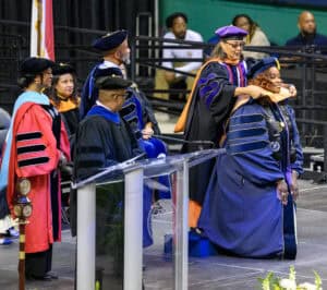 Graduation ceremony with faculty members in academic regalia at CAES News event.